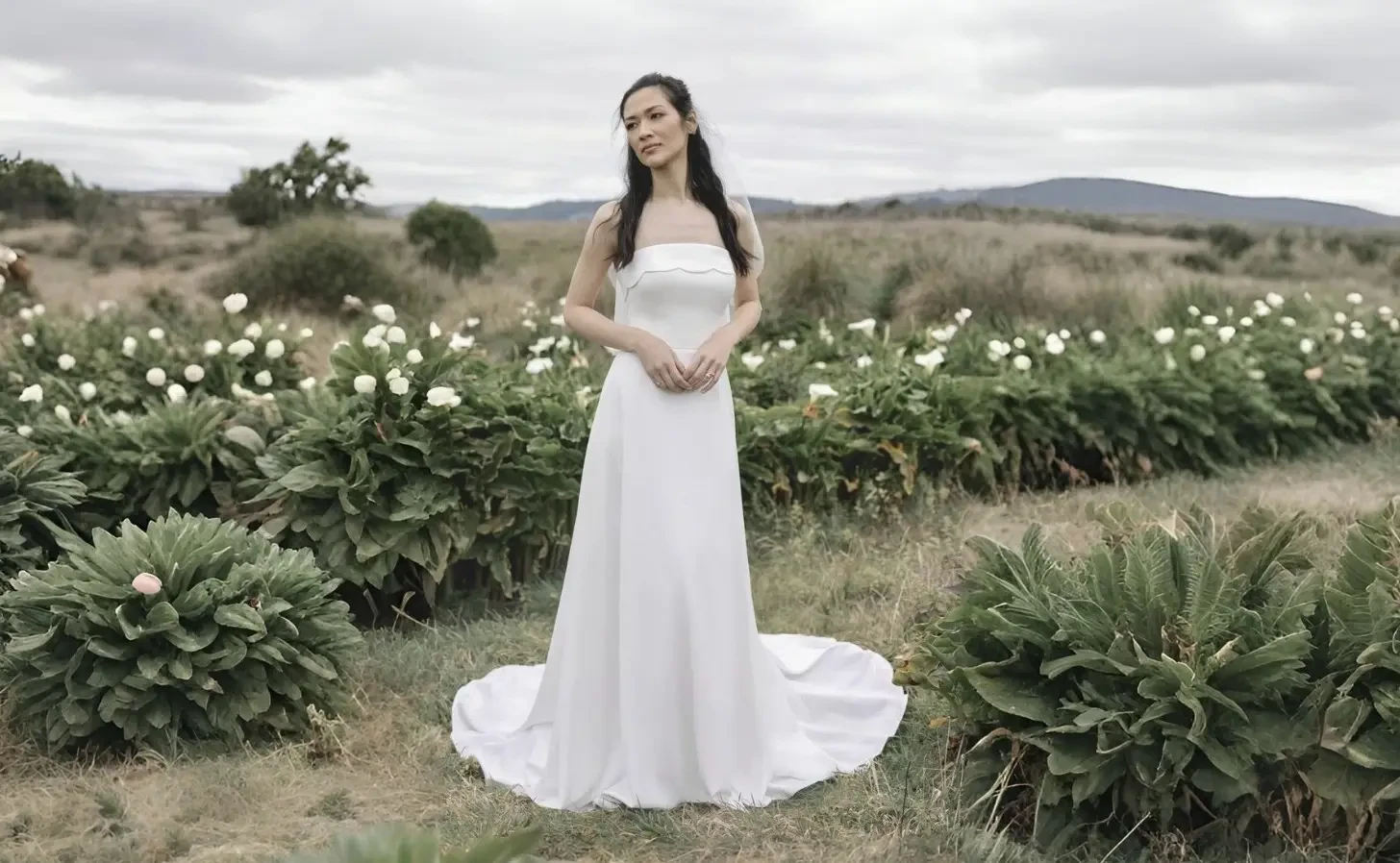 Bride and groom walking hand in hand in a garden.