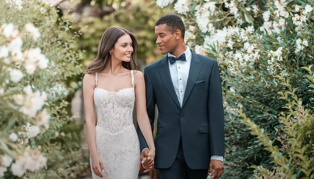 Bride and groom walking hand in hand in a garden.